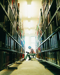 Young woman reading in library stack