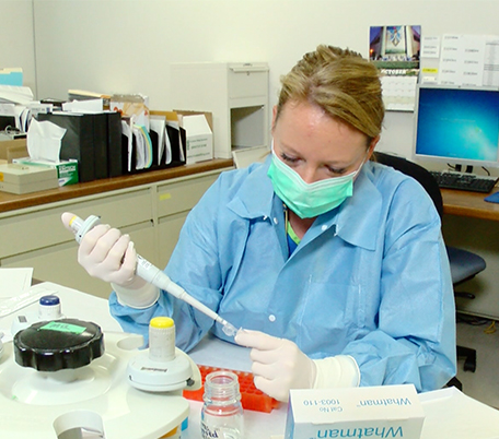 Photo of a crime lab scientist as she begins testing evidence from a sexual assault kit to determine if there is DNA present on a swab.