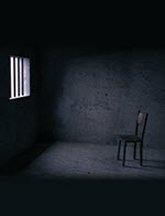 Light through a prison window onto a wooden chair.