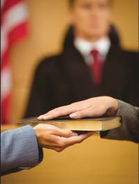 Hands on a book showing a witness being sworn in