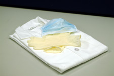 photo of a folded button down shirt with a mask and gloves on top