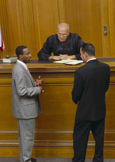 Photo of a judge talking with a defense attorney and a prosecutor