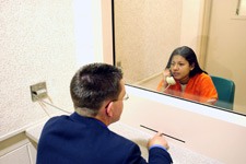 photo of a defense attorney to a defendant behind glass