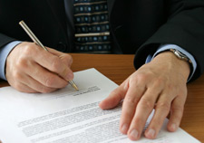 Photo of a man signing a piece of paper