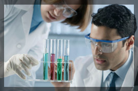 Photo of two chemists in a lab examining vials of data samples