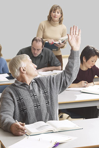Photo of an old man raising his hand in a classroom setting