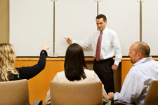 a man in front of a whiteboard talking to three people