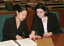 Photo of two women in suits examining a document in court.