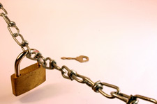 Photo of a padlock on a chain with a key in the background