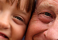 Close up photo of a young child and an old man with their faces together