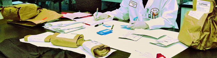 Lab worker sitting at a table with bags of evidence
