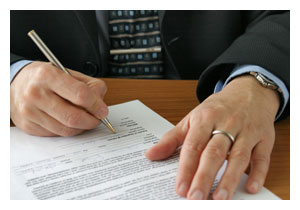 photo of a man's hands signing a piece of paper