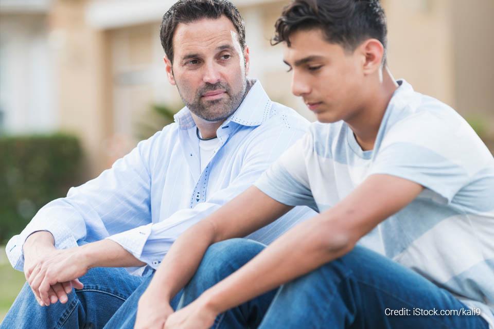 A man sitting next to a boy who is looking troubled. 