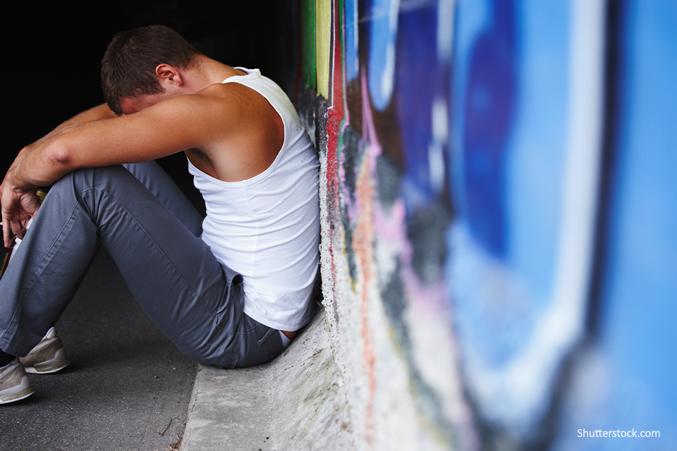 young person looking sad sitting down next to a wall