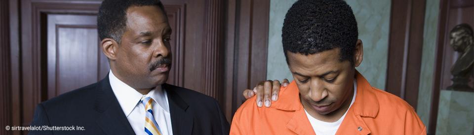 prisoner in orange jumpsuit in a courtroom with attorney