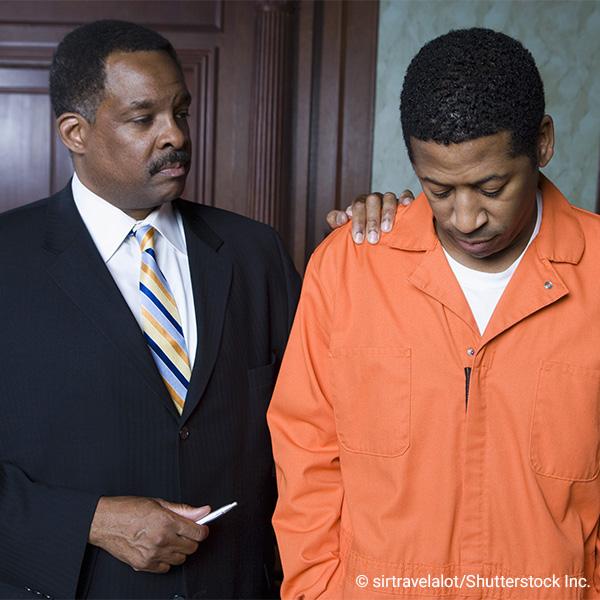 prisoner in orange jumpsuit in a courtroom with attorney