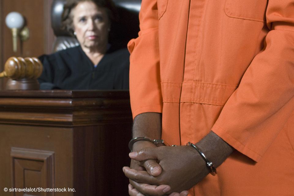 prisoner in orange jumpsuit in court with judge