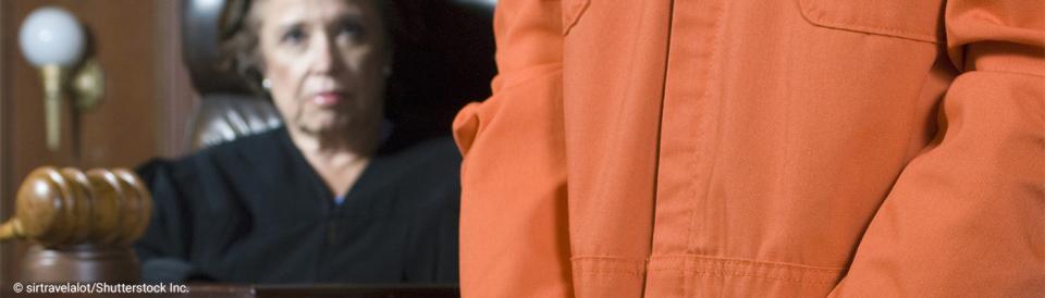 prisoner in orange jumpsuit in court with judge