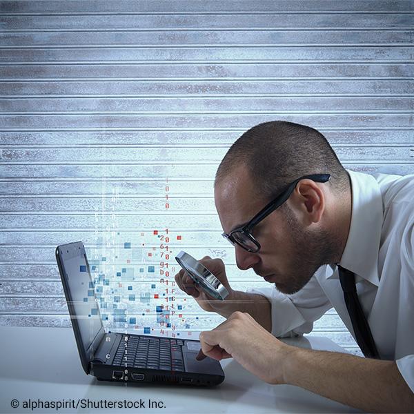 Man looking at laptop with magnifying glass