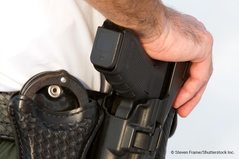 officer resting hand on a holstered handgun