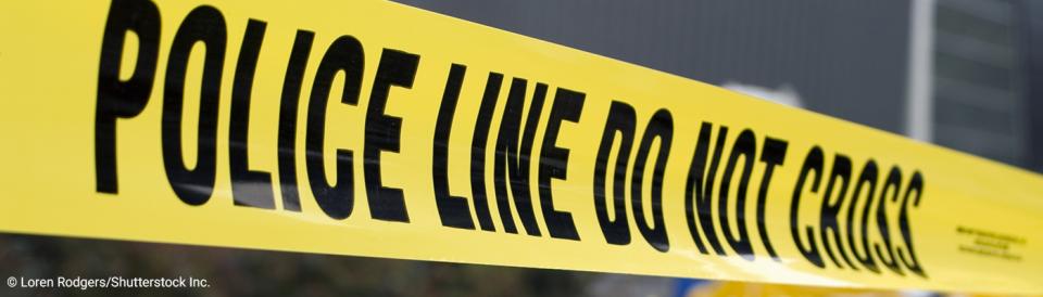 close-up of crime scene tape with first responders in background