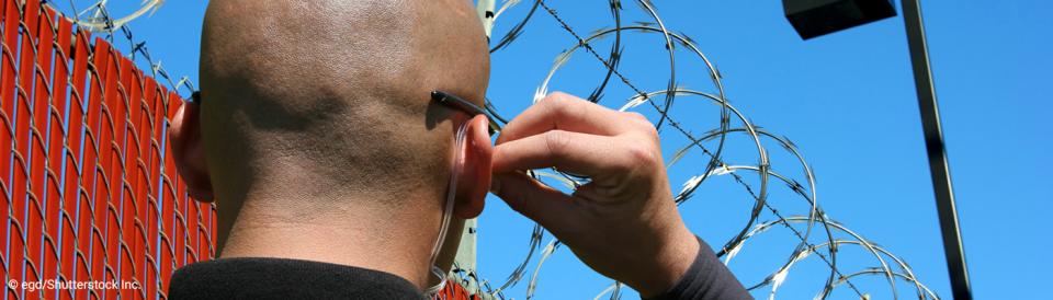 correctional officer next to a razor wire fence