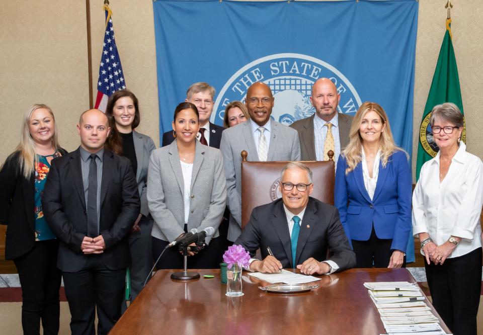 Lindsey Wade, in a gray blazer, stands next to Washington state governor, Jay Inslee. Jennifer Bastian’s mother, Pattie Bastian, is in the white blouse, on the right.