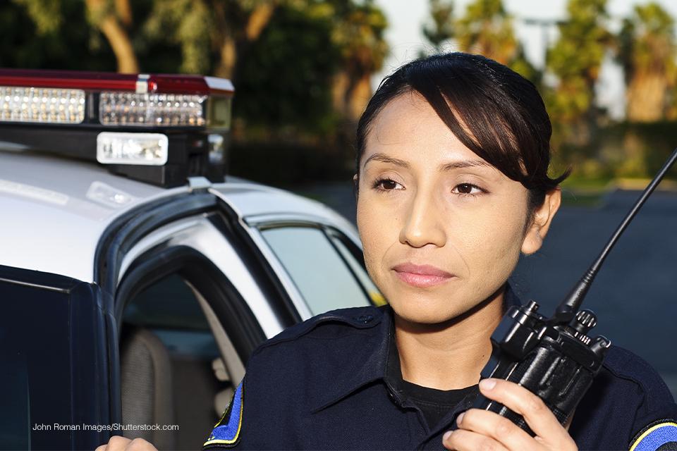 A public safety officer holding a walkie-talkie. They have dark hair and bangs.