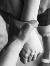 A person's hands being restrained by another person's hand.