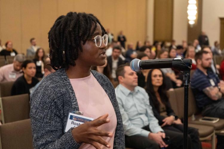 A conference attendee participants in Q&A after a plenary