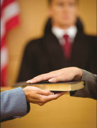 Hands on a book showing a witness being sworn in